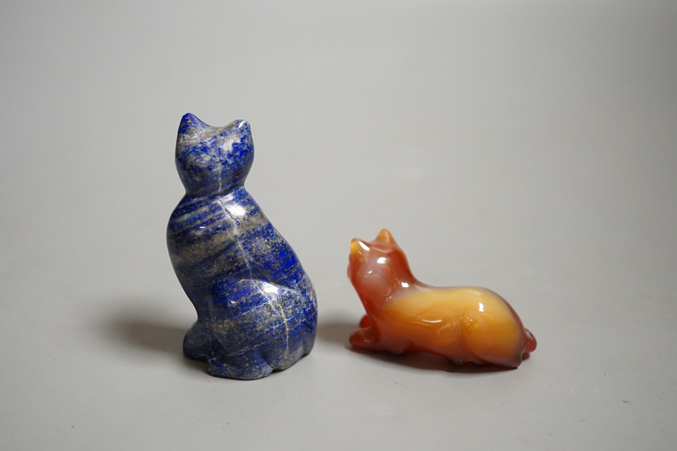 A Chinese carved lapis lazuli seated cat, a banded agate recumbent cat on hardwood stand and a white metal mounted agate scent bottle